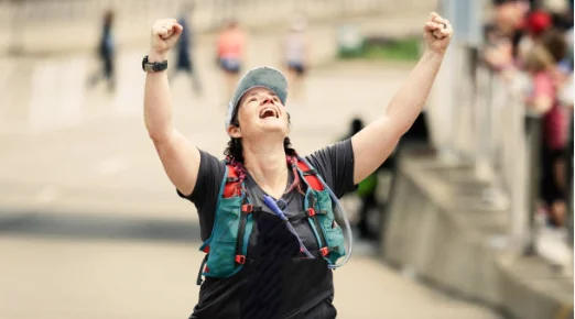 Erin finishing the Mesa marathon, arms raised